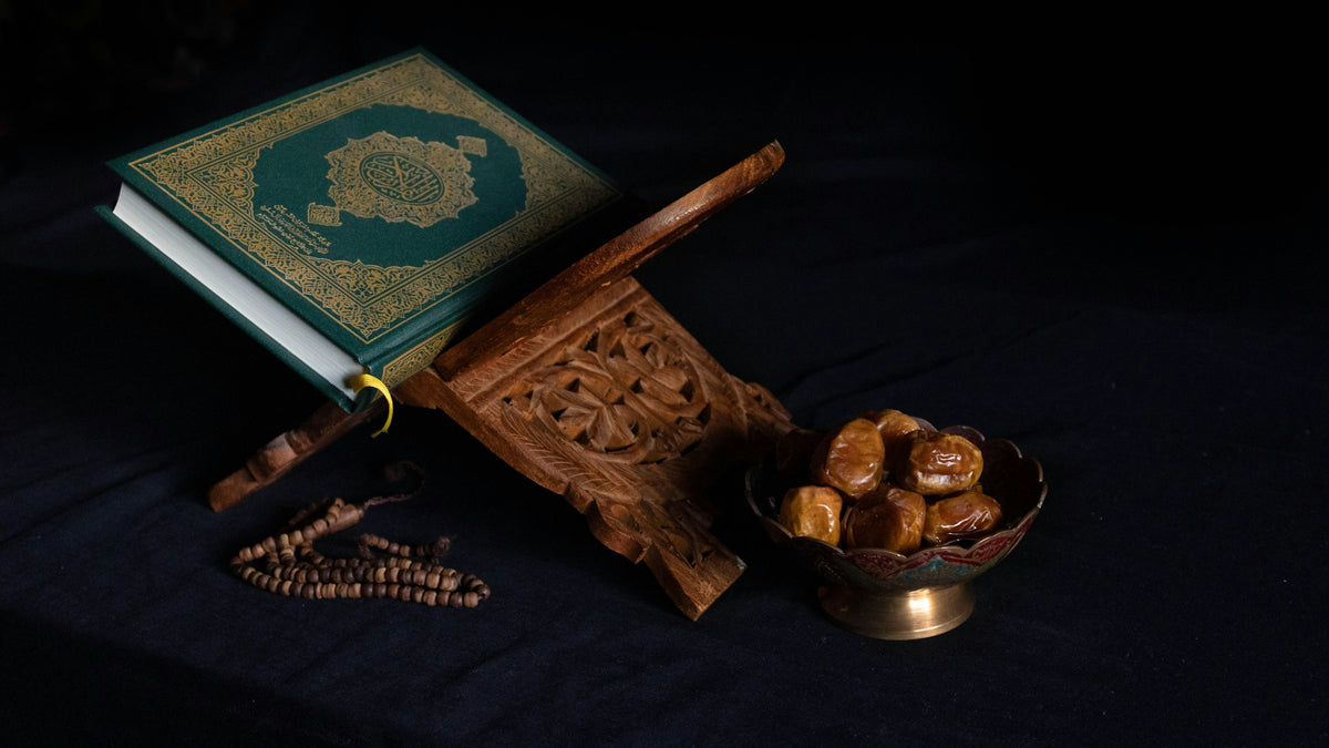 Quran auf einem Holzständer mit Datteln und Gebetskette